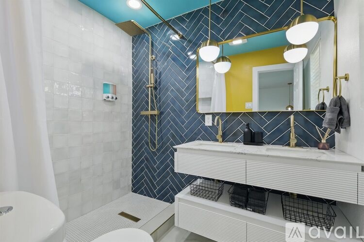 A bathroom with a white toilet, a white sink, and a blue tiled shower.