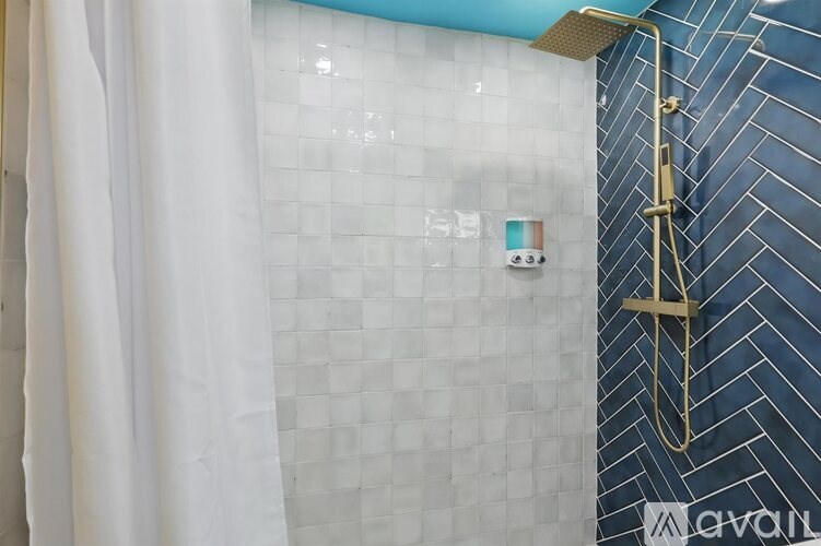 A shower area with a white curtain and a gold shower head.