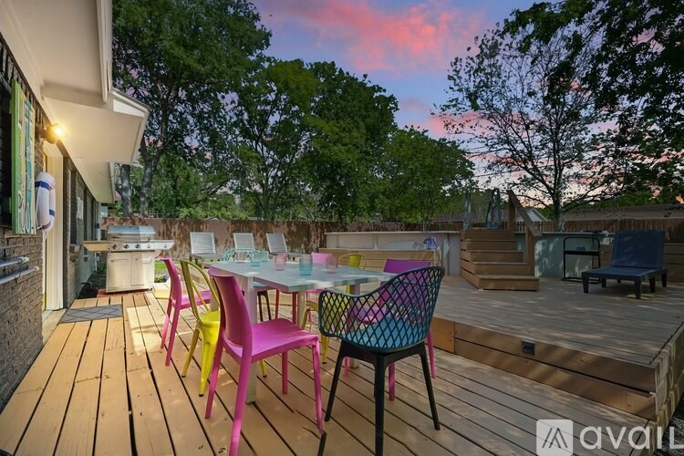 A wooden deck with a table and chairs is set up on a patio.