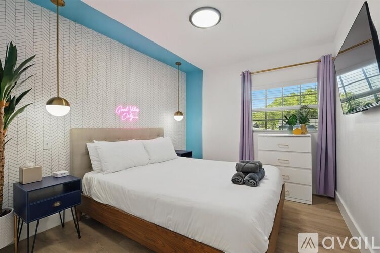 A bedroom with a bed, nightstand, and a plant.