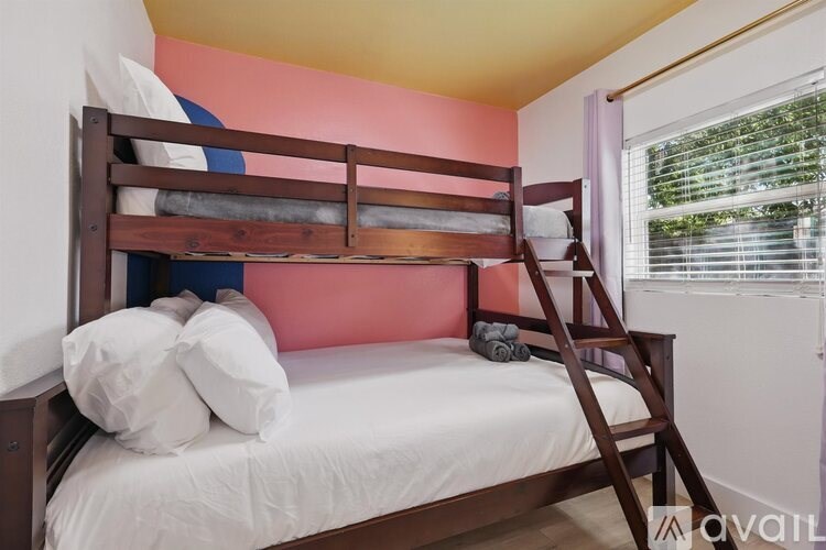 A bed with a white sheet and pillows is in a room with a wooden ladder.