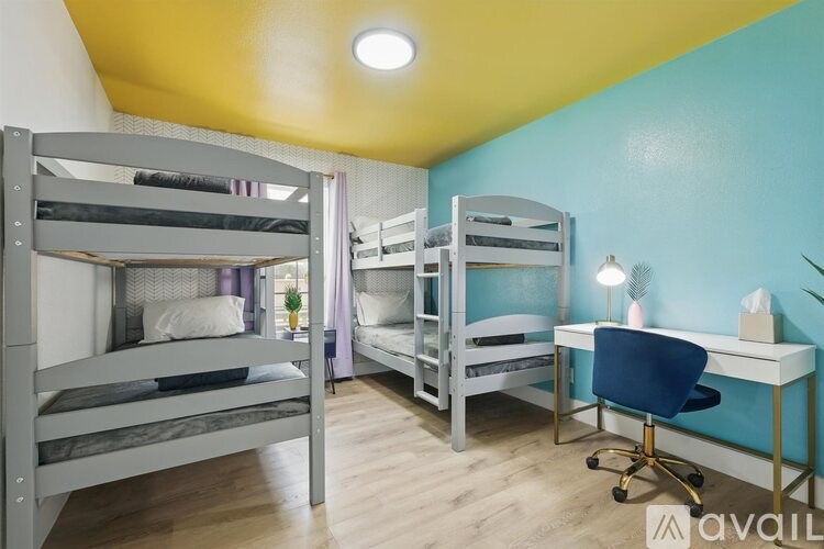 A room with bunk beds and a desk with a chair.