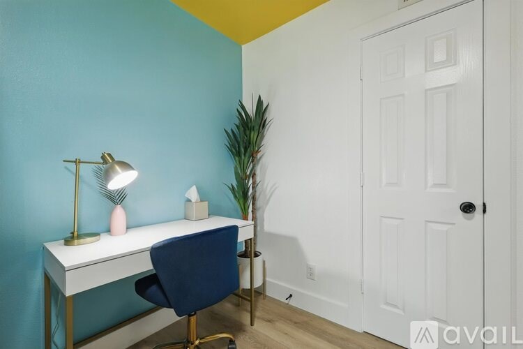 A desk with a blue chair and a lamp on it.