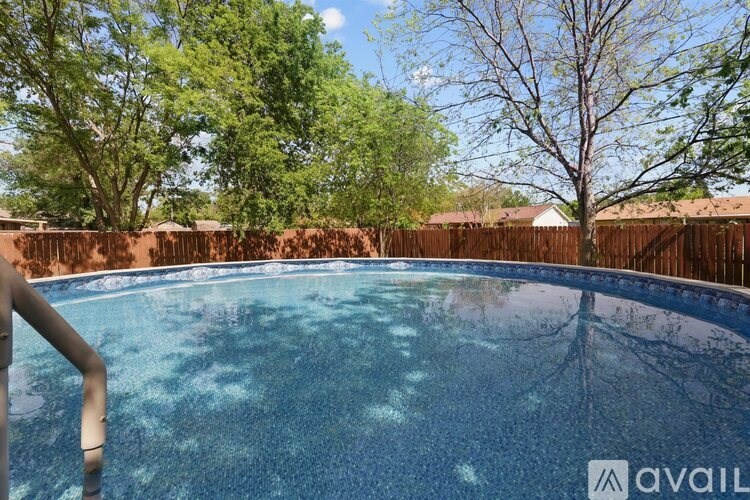 A pool surrounded by a wooden fence and trees.