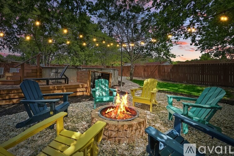 A backyard with a fire pit and chairs.