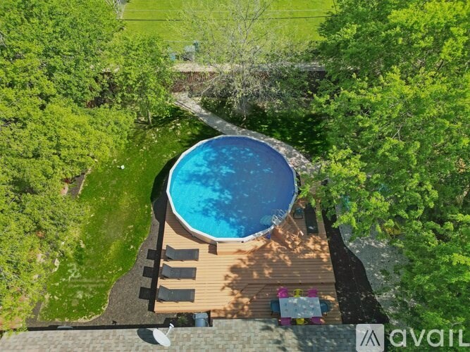 A small round pool surrounded by a wooden deck and trees.