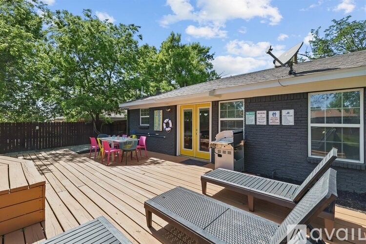 A wooden deck with a table and chairs is in front of a house.