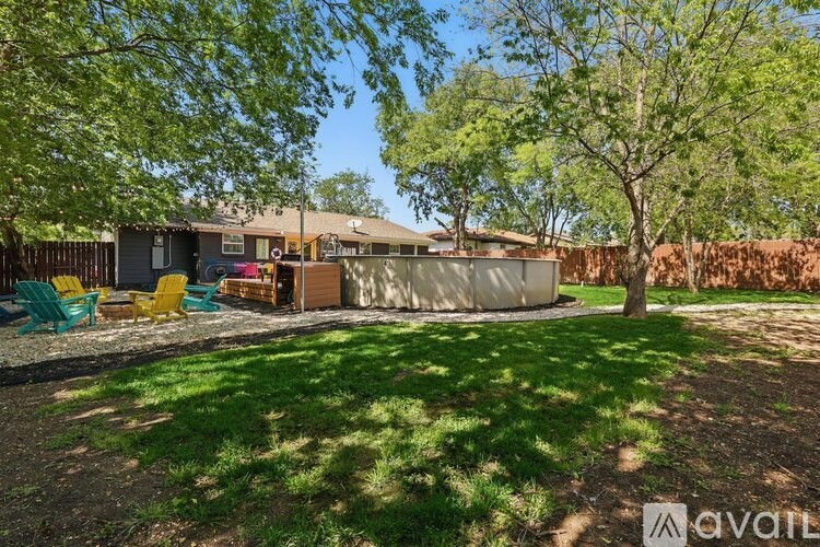 A backyard with a house, a tree, and a lawn.