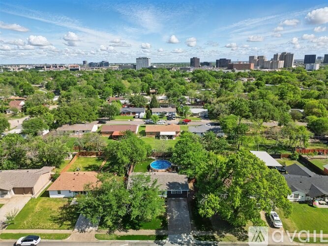A bird's eye view of a residential area with houses, trees, and a pool.