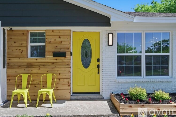 Two yellow chairs are placed on a concrete slab in front of a wooden door.