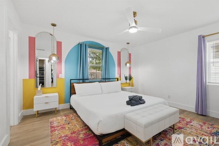 A bedroom with a white bed and a colorful accent wall.