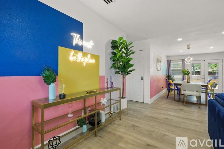 A living room with a blue and pink wall and a gold shelf.