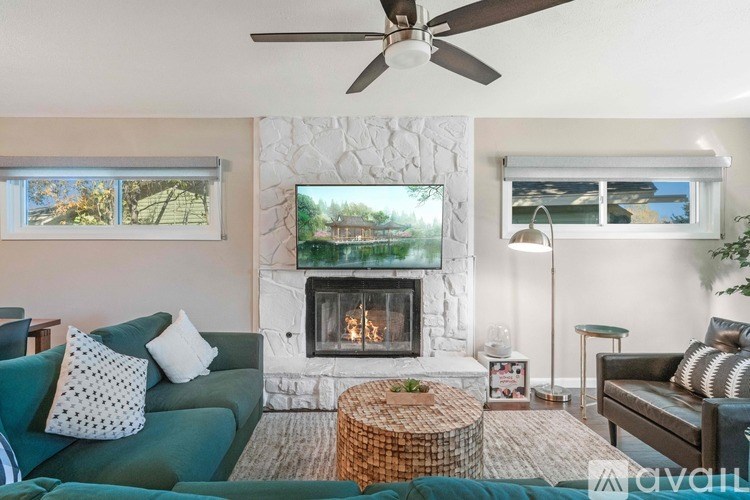 A living room with a fireplace and a painting of a house on the wall.