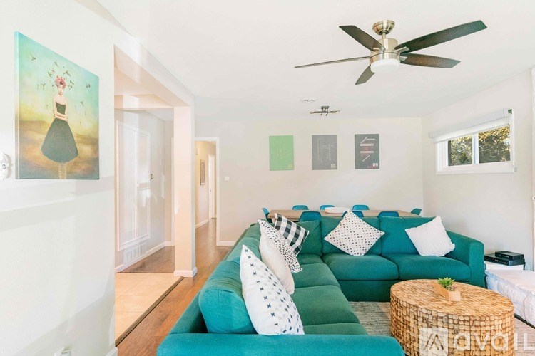 A living room with a green couch and a ceiling fan.