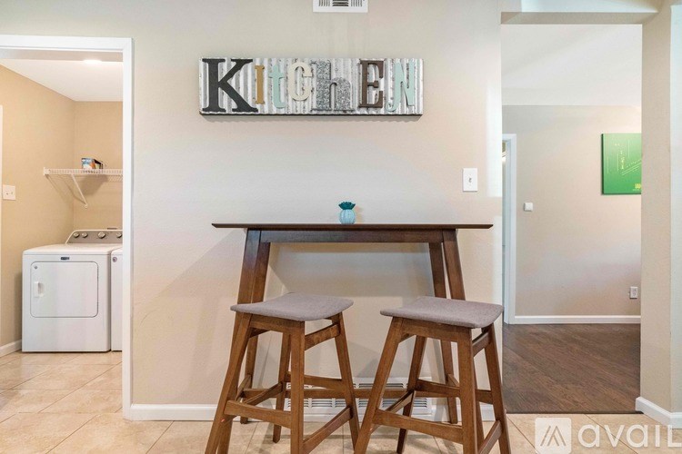 A kitchen area with a bar stool and a fridge.
