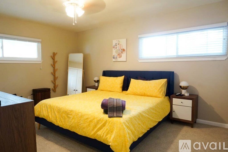 A bedroom with a yellow bedspread and a white dresser.