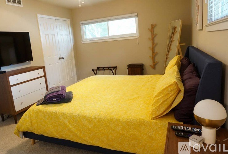 A bedroom with a bed covered in yellow bedding and a white lamp on the nightstand.