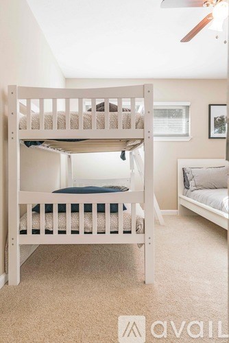 A white bunk bed with a single bed in the corner.