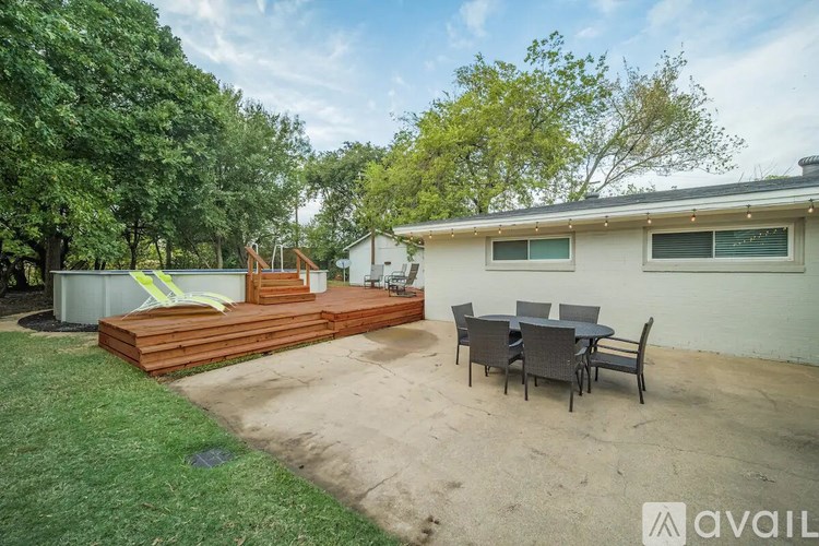 A backyard with a deck, patio furniture, and a house.