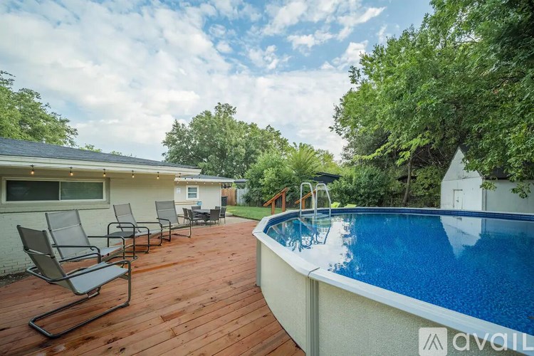 A pool with a deck and chairs in front of a house.