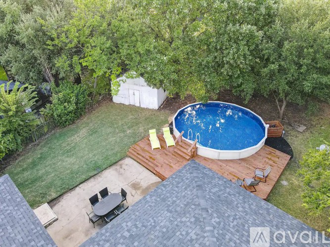 A pool surrounded by trees and a deck.