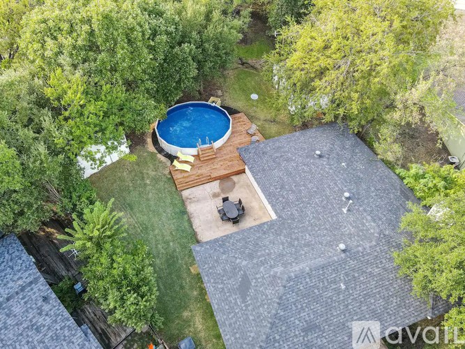 A backyard with a pool and a hot tub surrounded by trees.