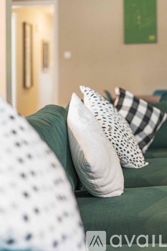 A couch with a green cushion and a white pillow with black dots.