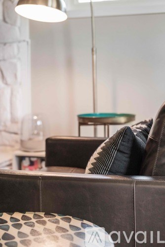 A brown couch with a pillow and a lamp above it.