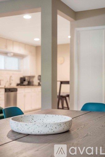 A bowl with a speckled pattern sits on a wooden table in a modern kitchen.