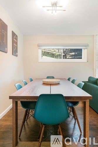 A long wooden table with a white bowl on it and blue chairs.