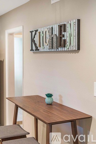 A kitchen sign is on the wall above a table.