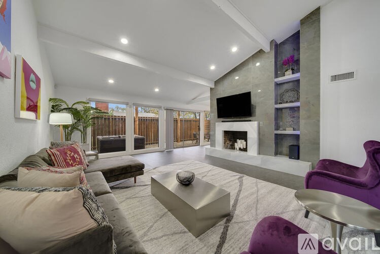 A modern living room with a grey sofa, a purple armchair, and a fireplace.