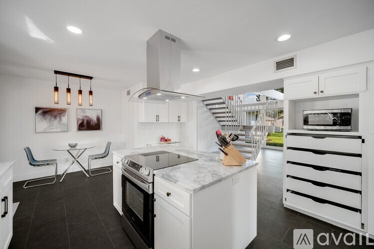 A modern kitchen with white appliances and a black floor.