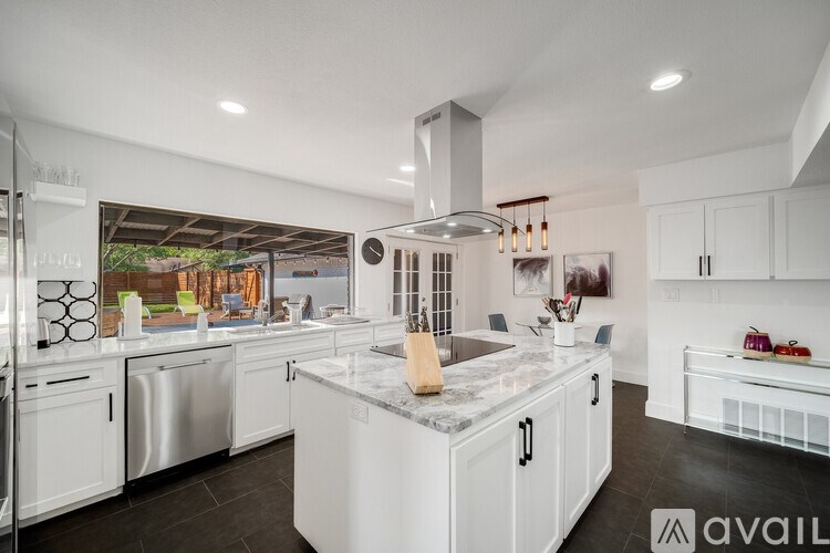 A modern kitchen with white cabinets and a marble island.