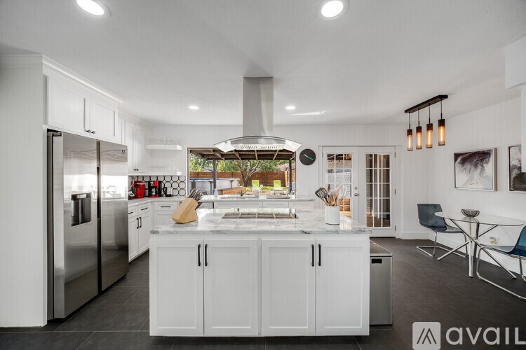 A modern kitchen with white cabinets and stainless steel appliances.