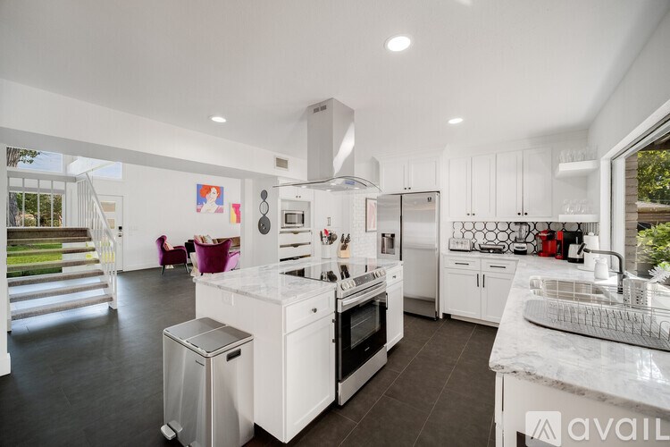 A modern kitchen with white cabinets and a marble countertop.