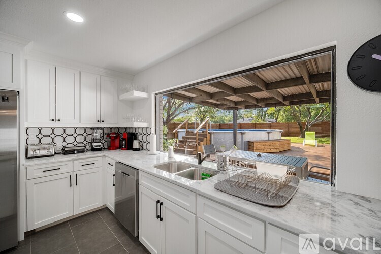 A kitchen with white cabinets and a marble countertop.