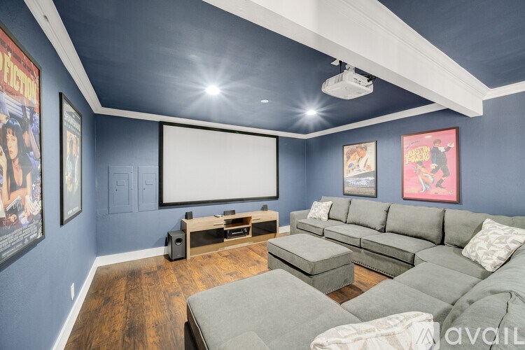 A living room with a grey sofa set and a white screen.