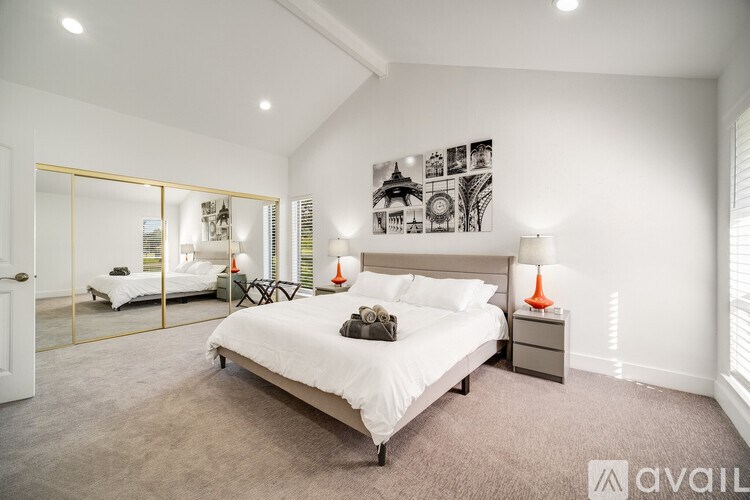 A bedroom with a large bed, a mirror, and a wall with pictures.