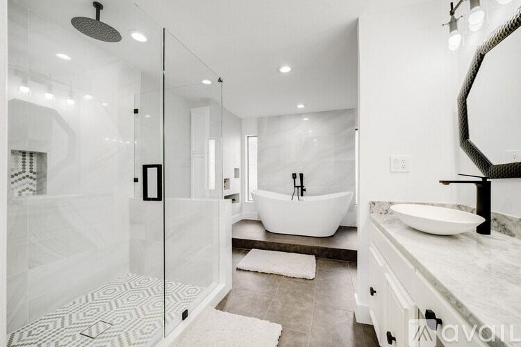 A modern bathroom with a white tub, sink, and a glass shower.