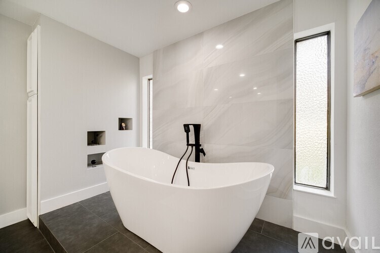 A white freestanding bathtub in a modern bathroom.