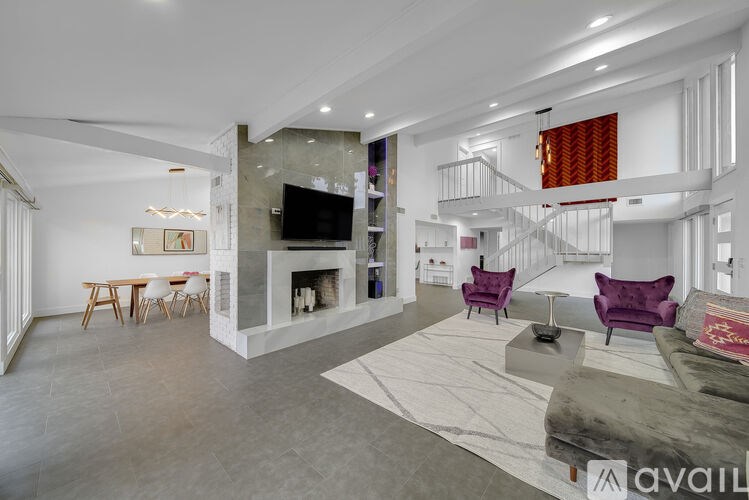 A modern living room with purple chairs and a grey rug.