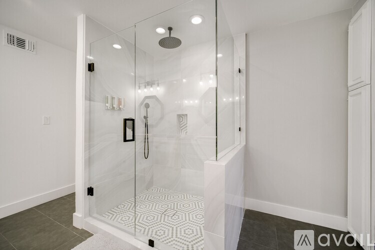 A modern bathroom with a glass shower enclosure and a white tiled floor.