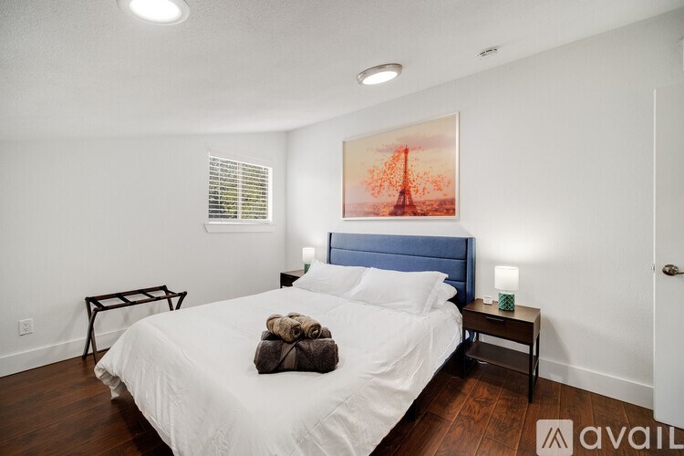 A bedroom with a large bed and a painting on the wall.