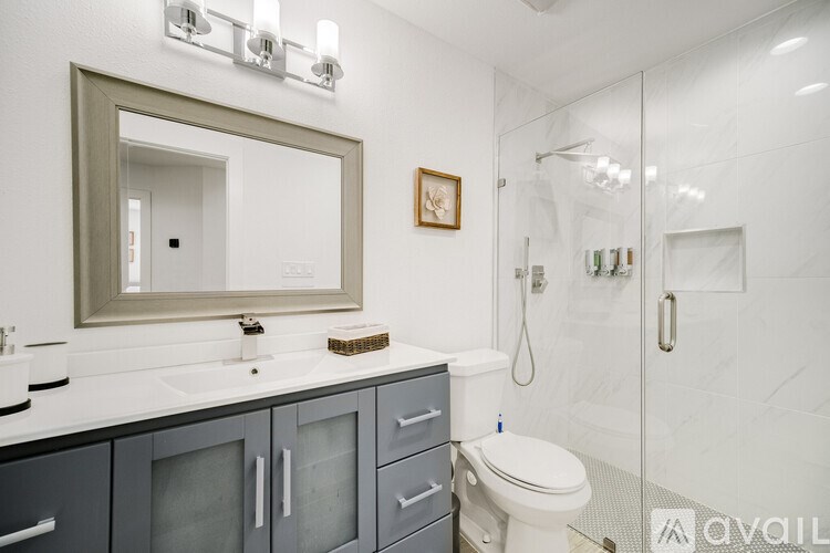 A bathroom with a toilet, sink, and mirror.