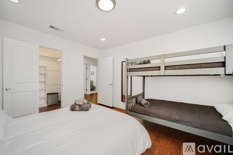 A bedroom with a white bed and a bunk bed.