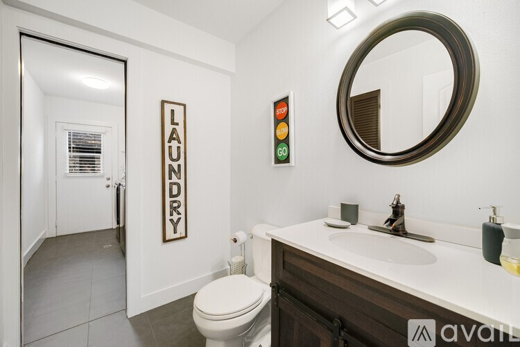 A bathroom with a toilet, sink, mirror, and a laundry sign.