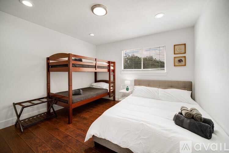 A bedroom with a bunk bed and a white bed.