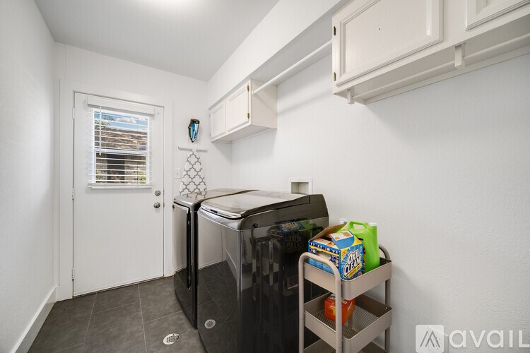 A kitchen with a black fridge, a white door, and a window with blinds.