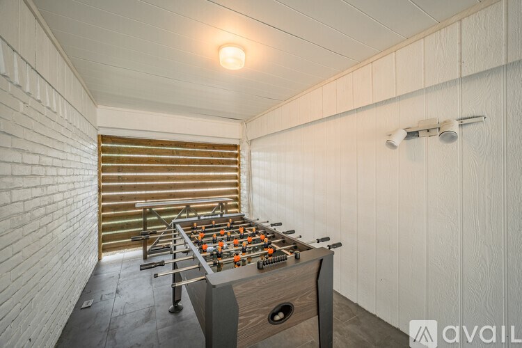 A foosball table in a room with white walls and a wooden floor.